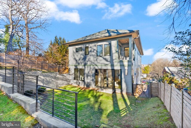 rear view of property featuring a balcony and a lawn