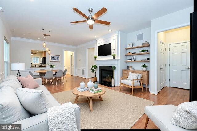 living room with ceiling fan, crown molding, and light hardwood / wood-style floors