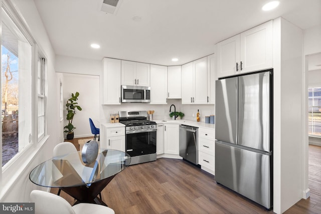 kitchen with appliances with stainless steel finishes, sink, dark wood-type flooring, and white cabinets