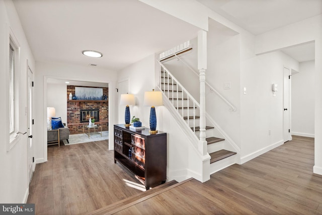 stairs with a brick fireplace and hardwood / wood-style floors