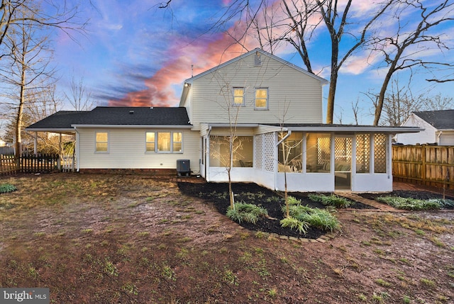 back house at dusk with a sunroom and central air condition unit