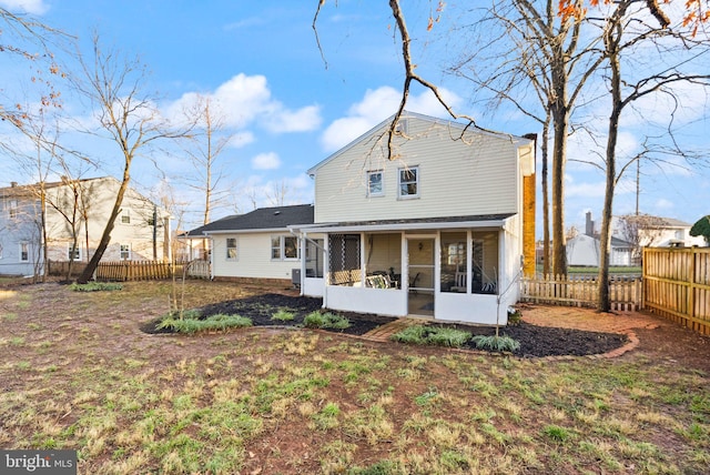 back of house with a sunroom and a lawn