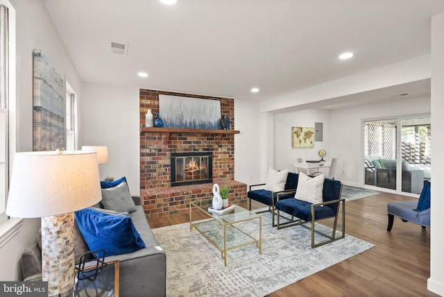 living room with a brick fireplace and wood-type flooring