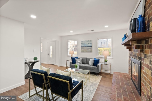 living room featuring a brick fireplace and hardwood / wood-style flooring