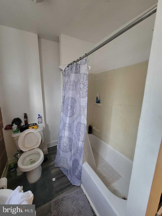 full bathroom featuring toilet, baseboards, wood finished floors, and shower / tub combo with curtain