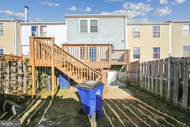 rear view of house with a wooden deck and a lawn