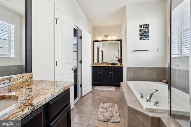 bathroom with vanity, tile patterned flooring, and a relaxing tiled tub