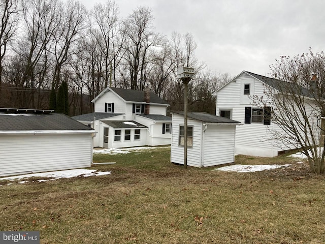 rear view of property with a storage shed and a lawn