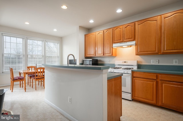 kitchen with sink, white range with gas stovetop, and a center island with sink