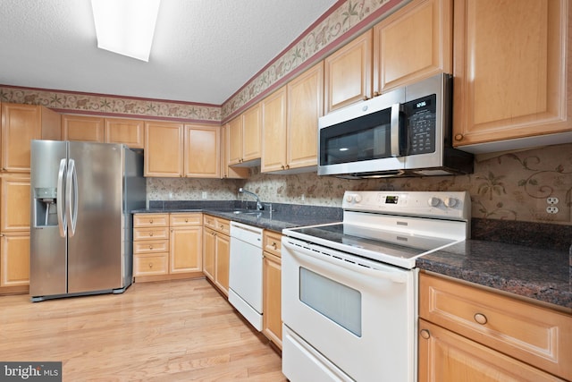 kitchen featuring sink, light hardwood / wood-style flooring, stainless steel appliances, a textured ceiling, and light brown cabinets