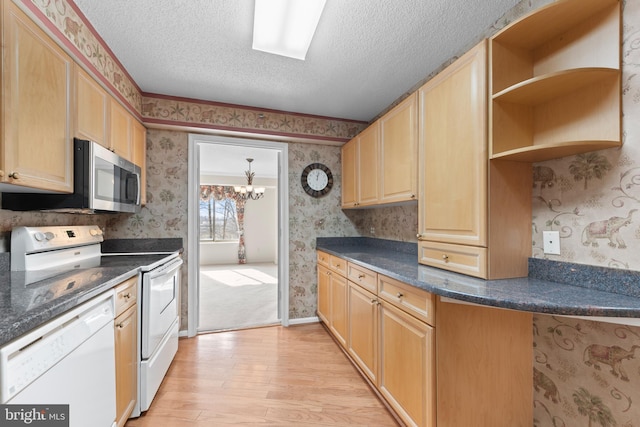 kitchen with an inviting chandelier, a textured ceiling, light brown cabinets, light hardwood / wood-style flooring, and white appliances