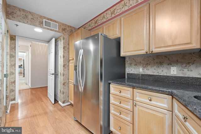 kitchen featuring a textured ceiling, stainless steel fridge, light brown cabinetry, and light hardwood / wood-style floors