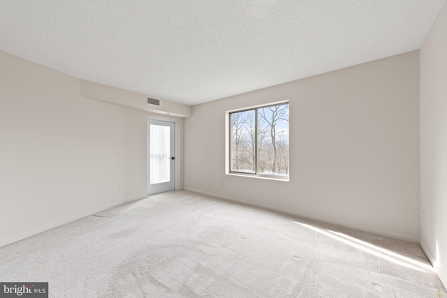 carpeted empty room featuring a textured ceiling