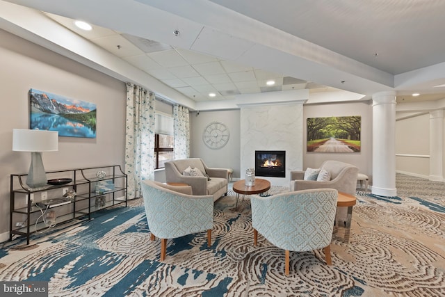 carpeted living room featuring a premium fireplace and decorative columns