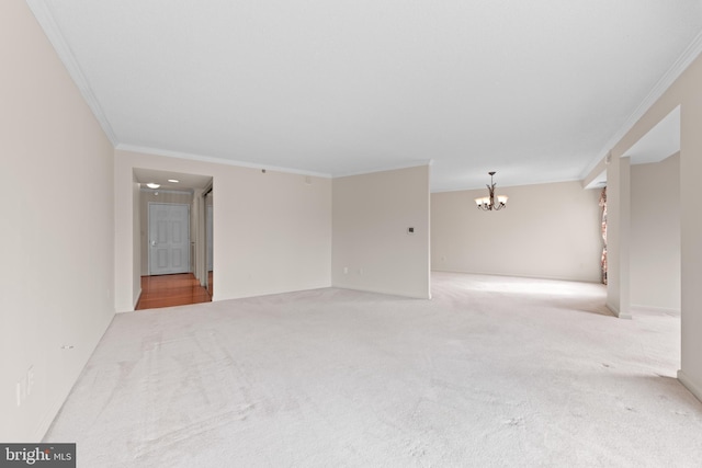 carpeted spare room with an inviting chandelier and crown molding