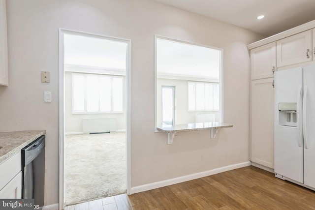 kitchen featuring white cabinets, light stone countertops, white fridge with ice dispenser, and dishwasher