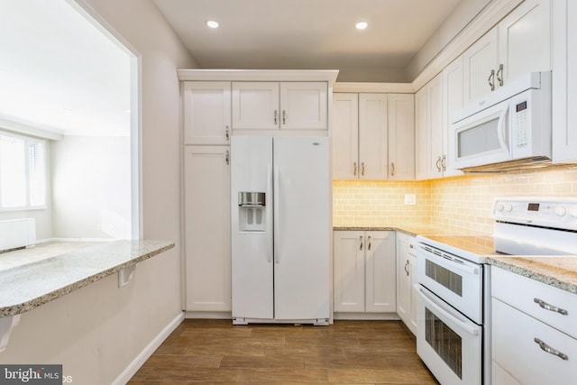 kitchen with white cabinetry, light stone countertops, and white appliances