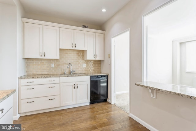 kitchen with white cabinetry, backsplash, light stone countertops, and black dishwasher