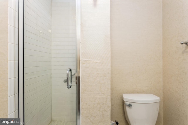 bathroom with toilet and a shower with door