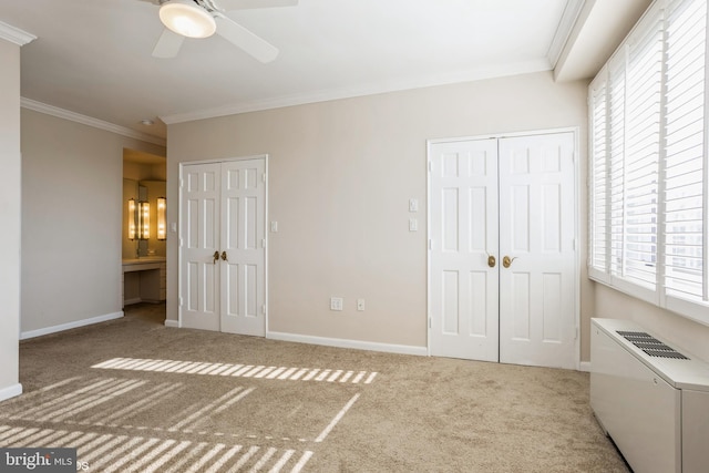 unfurnished bedroom featuring crown molding, ensuite bath, light carpet, and two closets