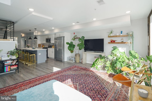 living room with visible vents, recessed lighting, light wood-type flooring, and stairs