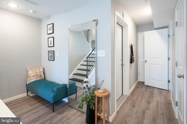 corridor featuring baseboards, wood finished floors, and stairs