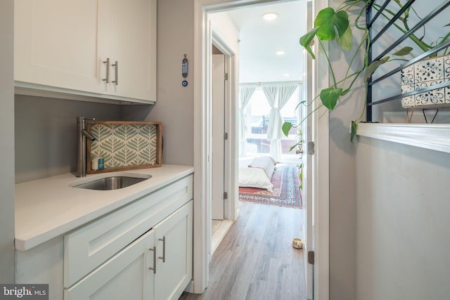 hallway with light wood-style floors and a sink