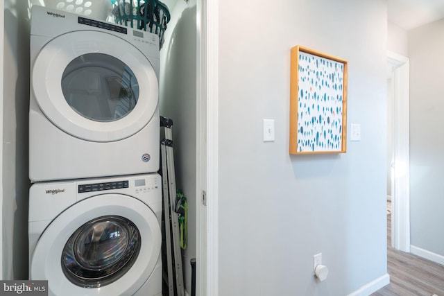 washroom featuring laundry area, wood finished floors, baseboards, and stacked washer and dryer