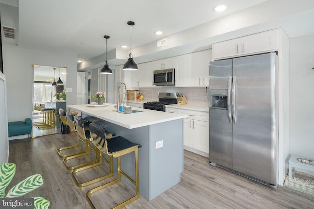 kitchen with a sink, decorative backsplash, stainless steel appliances, white cabinets, and light wood-style floors