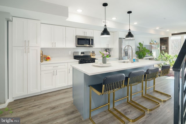 kitchen with backsplash, light countertops, light wood-style floors, white cabinets, and stainless steel appliances