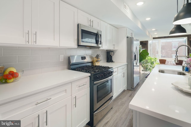 kitchen featuring decorative backsplash, white cabinetry, stainless steel appliances, and a sink