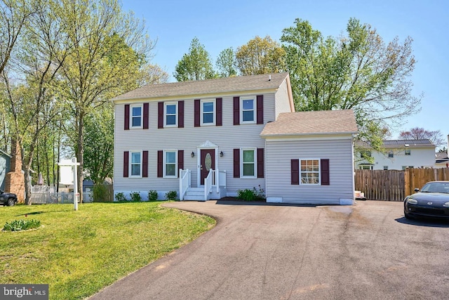 colonial-style house featuring a front lawn