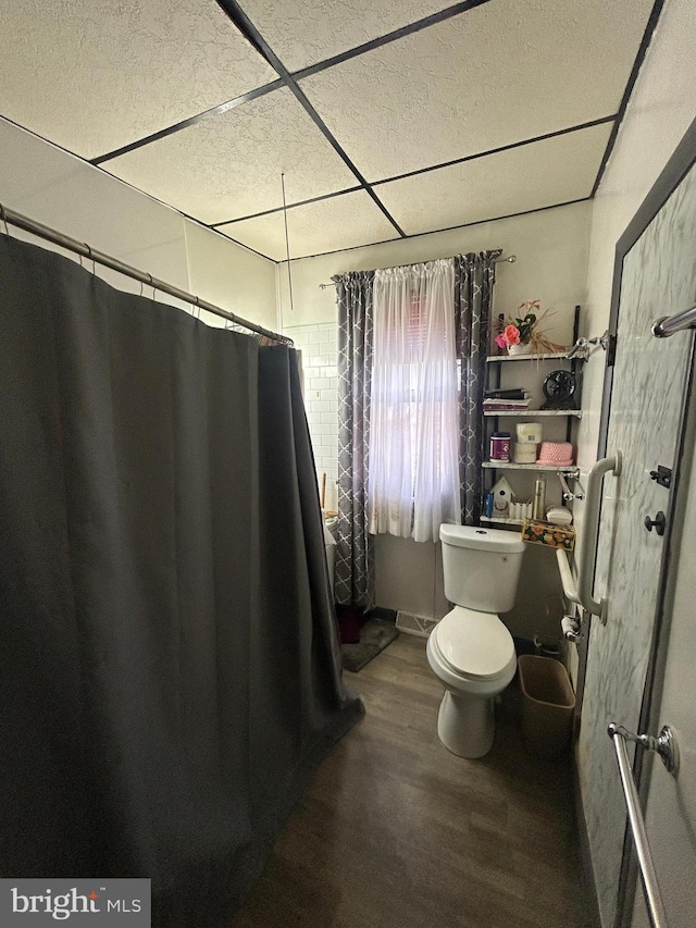 bathroom featuring toilet, a paneled ceiling, a shower with curtain, and wood finished floors