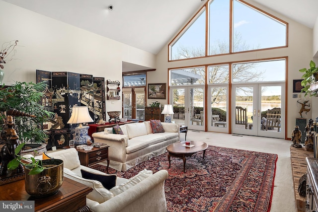 carpeted living room with high vaulted ceiling, french doors, and a water view