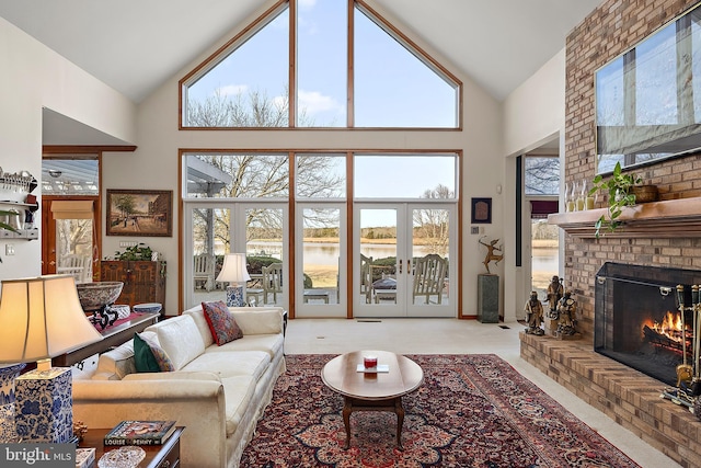 carpeted living room featuring a fireplace, high vaulted ceiling, french doors, and a water view