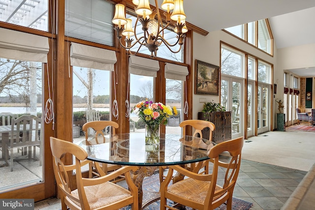 carpeted dining room with french doors, high vaulted ceiling, and a notable chandelier