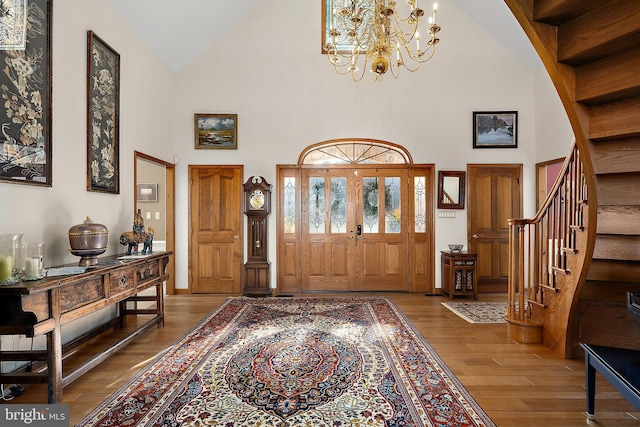 foyer with hardwood / wood-style flooring, high vaulted ceiling, and a notable chandelier