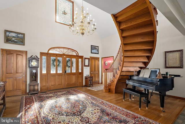 entryway with an inviting chandelier, hardwood / wood-style floors, and a towering ceiling