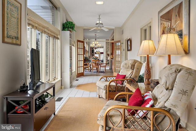 living area with ceiling fan with notable chandelier and light tile patterned flooring