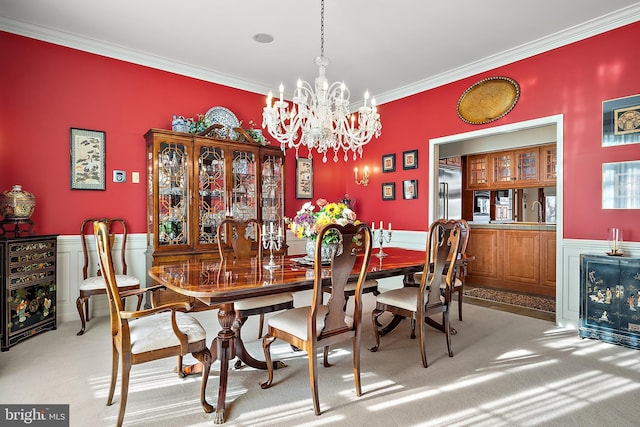 carpeted dining room featuring an inviting chandelier and ornamental molding