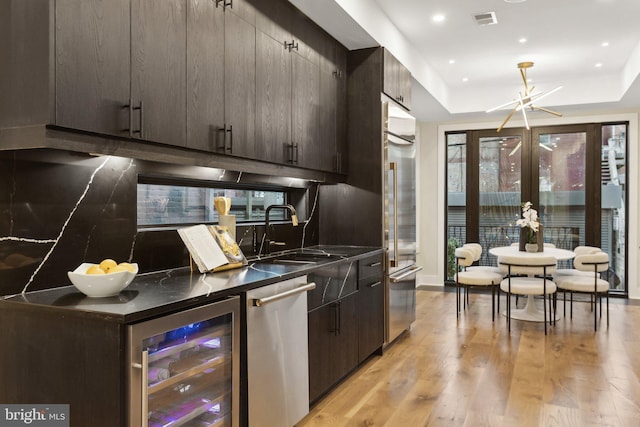 kitchen featuring sink, stainless steel appliances, wine cooler, tasteful backsplash, and a raised ceiling