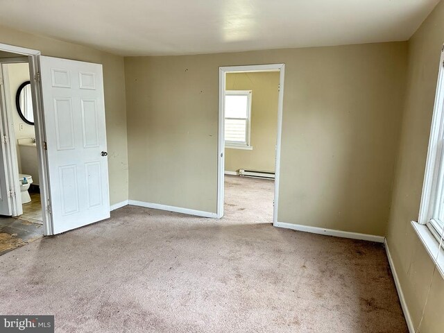 unfurnished room featuring carpet flooring and baseboard heating