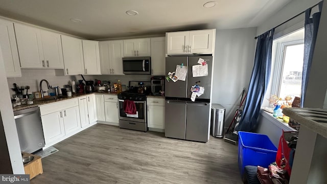 kitchen featuring sink, tasteful backsplash, appliances with stainless steel finishes, light hardwood / wood-style floors, and white cabinets