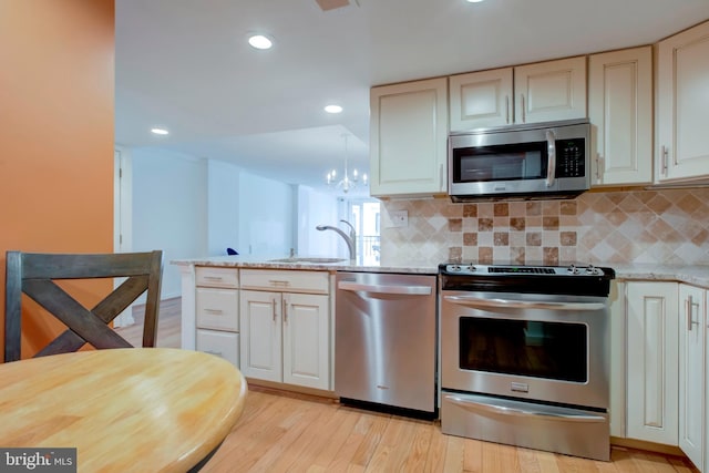 kitchen featuring sink, light hardwood / wood-style flooring, stainless steel appliances, light stone countertops, and backsplash