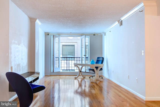 office area featuring light wood-type flooring, a textured ceiling, and a wealth of natural light