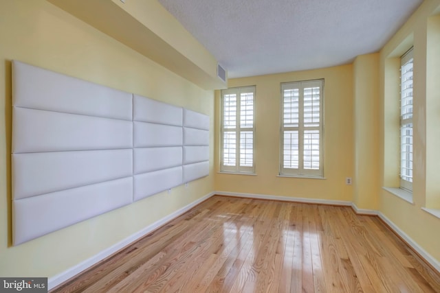 spare room with light hardwood / wood-style floors and a textured ceiling