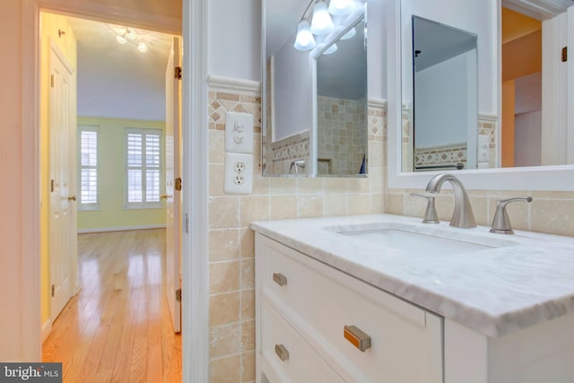 bathroom with hardwood / wood-style floors, vanity, and tile walls