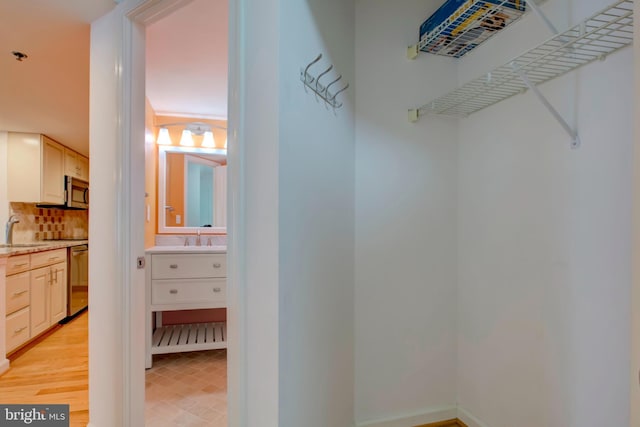 walk in closet with sink and light wood-type flooring