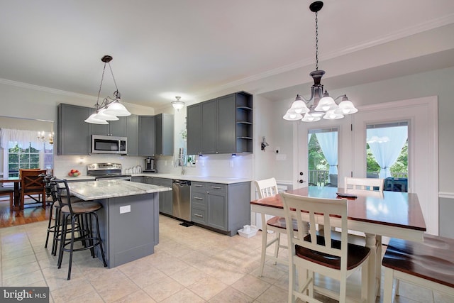 kitchen with pendant lighting, a center island, appliances with stainless steel finishes, and gray cabinets