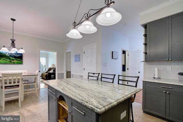 kitchen with tasteful backsplash, crown molding, hanging light fixtures, gray cabinets, and a kitchen island